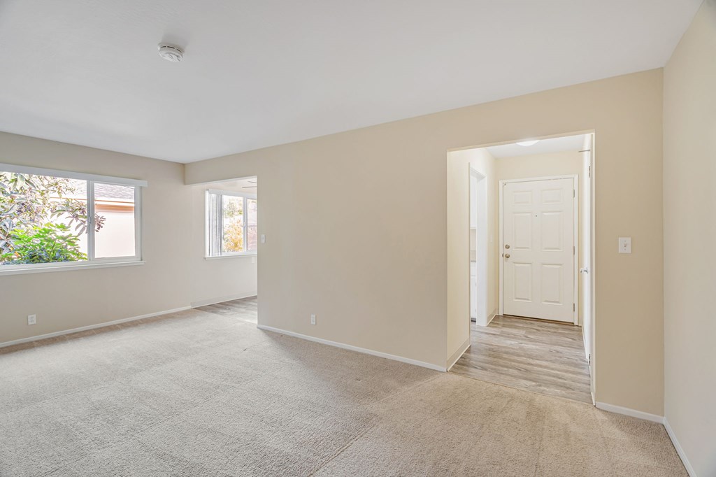 A room with a carpeted floor and a door leading to another room.