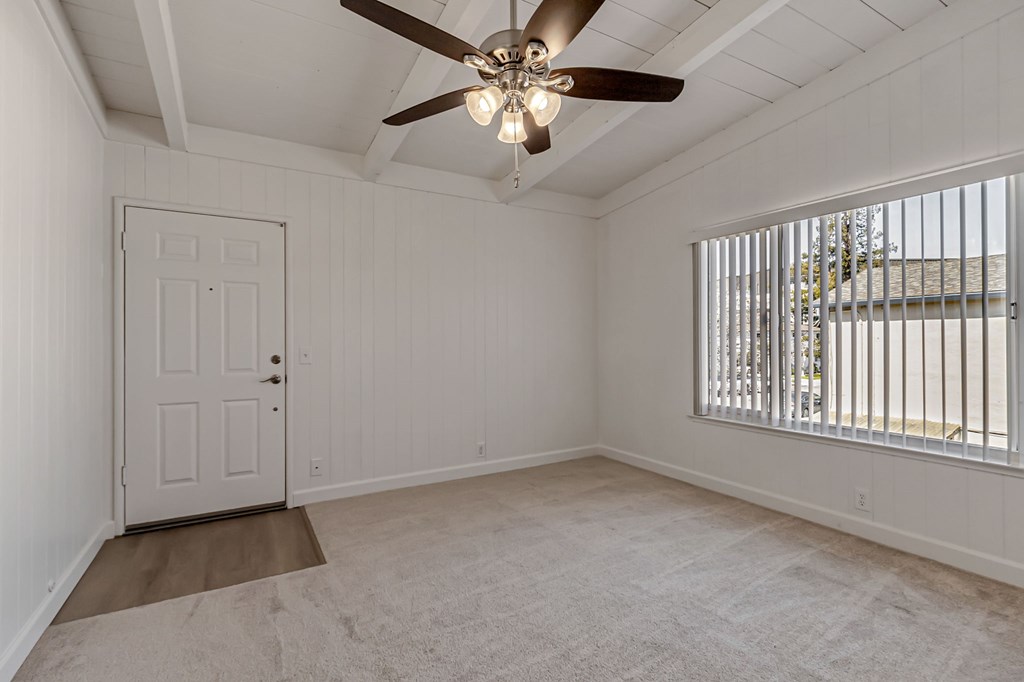 A room with a ceiling fan and a door.