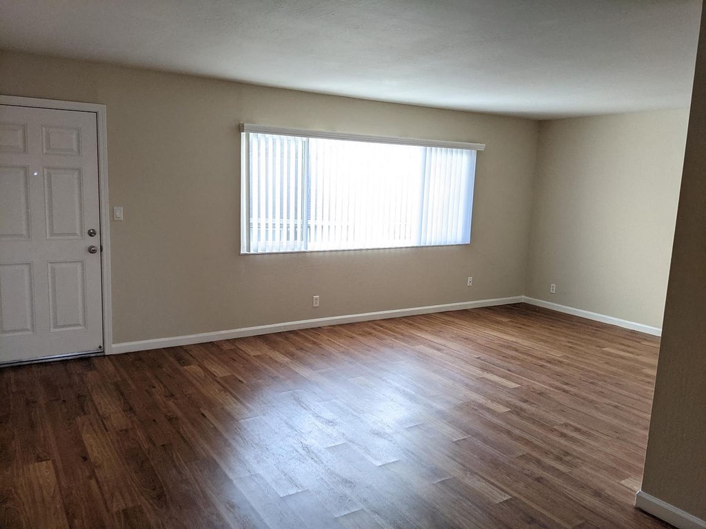 A room with wooden flooring and a window with blinds.