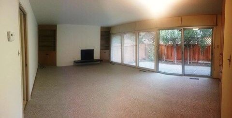 A living room with a flat screen TV and sliding glass doors.