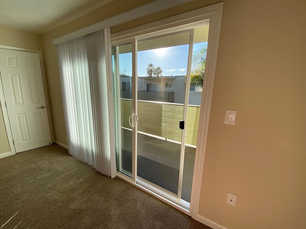 A room with a sliding glass door leading to a balcony.