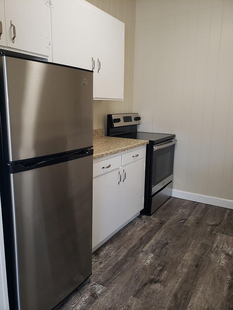 A kitchen with a stainless steel refrigerator and white cabinets.