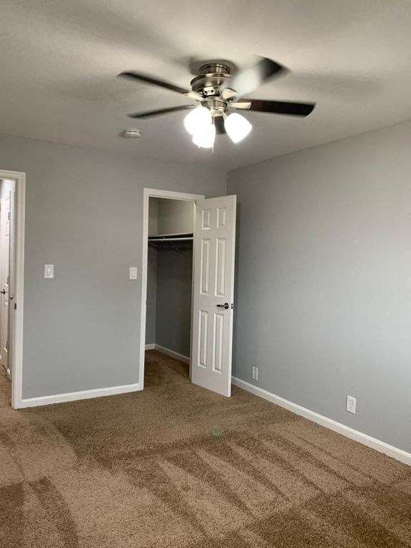 A room with a ceiling fan and carpeted floor.