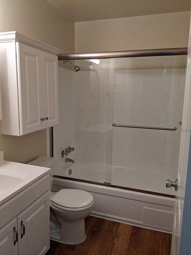 A white toilet sits under a mirror in a bathroom.