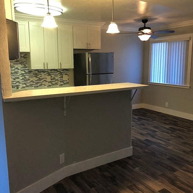 A kitchen with a refrigerator, cabinets, and a countertop.