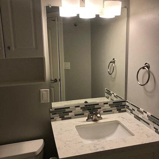 A bathroom with a marble counter top and a white sink.