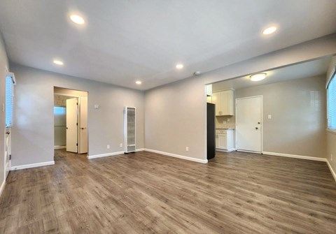 A spacious room with wooden flooring and white walls.