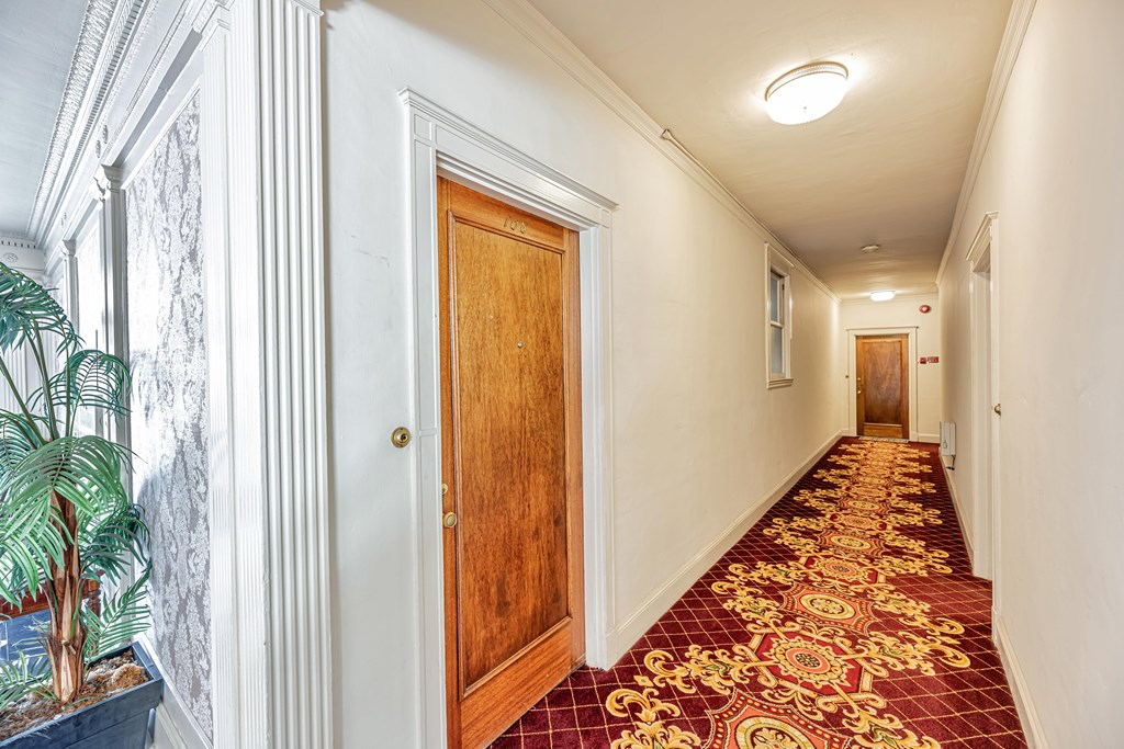 A long hallway with a red carpet and white walls.
