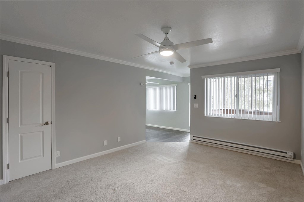A room with a ceiling fan and a window with blinds.