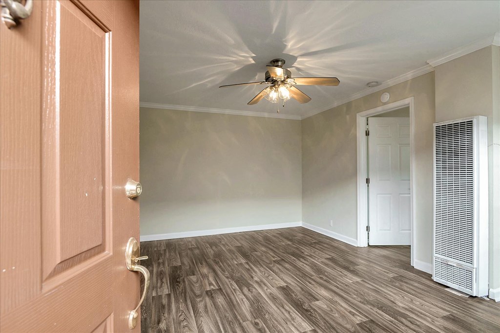 an empty living room with a ceiling fan and a door