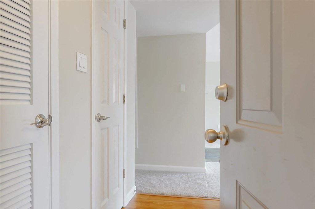 a bedroom with white walls and a door open to a hallway