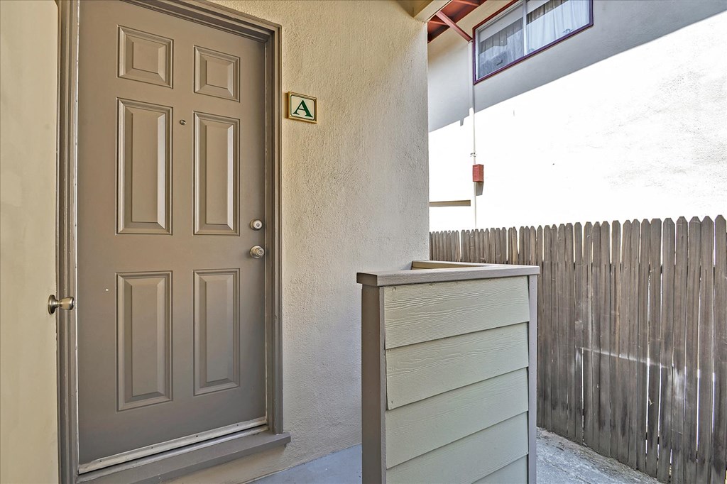 the front door of an apartment with a dresser and a fence