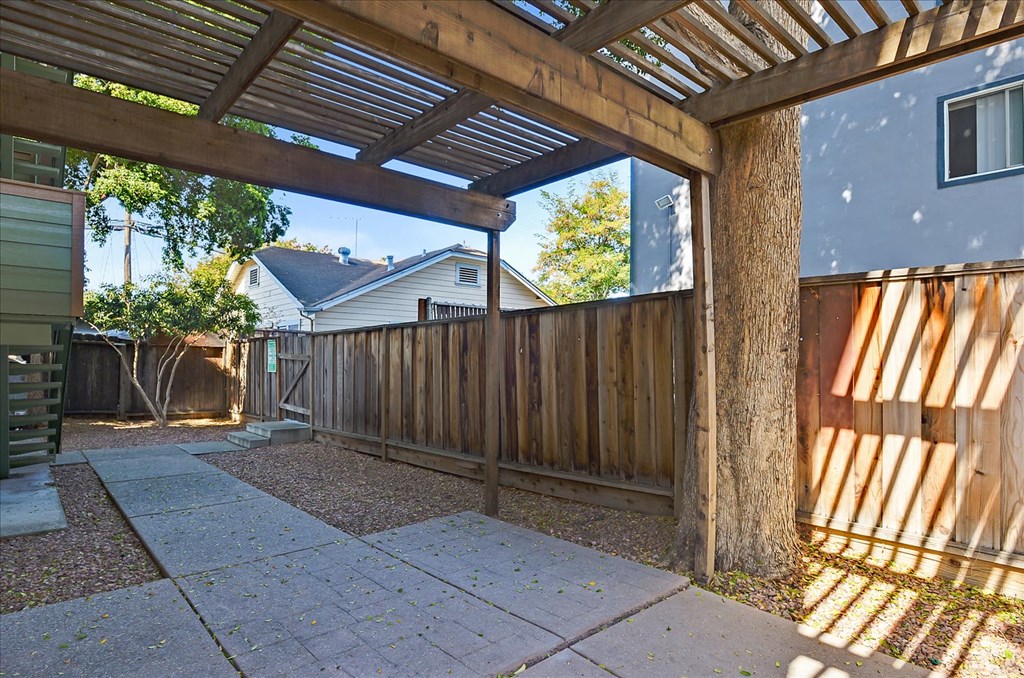 a backyard with a wooden fence and a walkway with a pergola