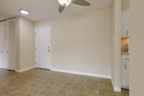 an empty living room with a ceiling fan and a closet