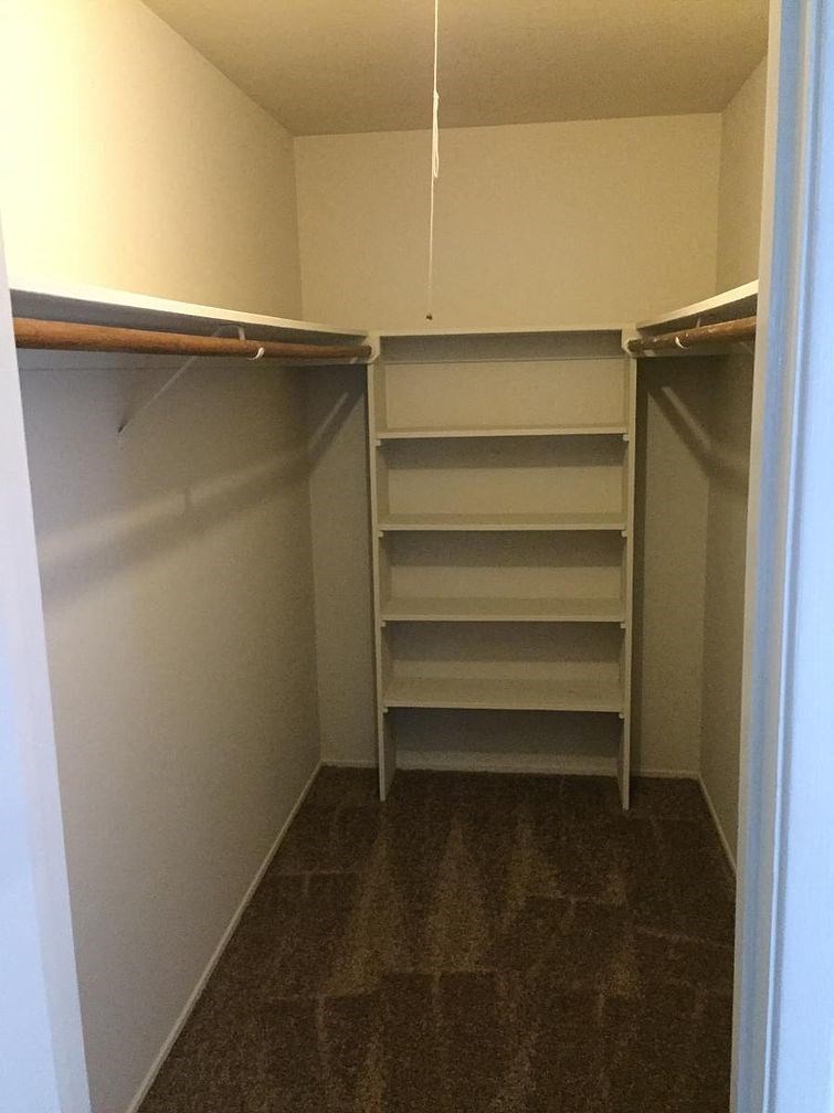 A small closet with a carpeted floor and white walls.