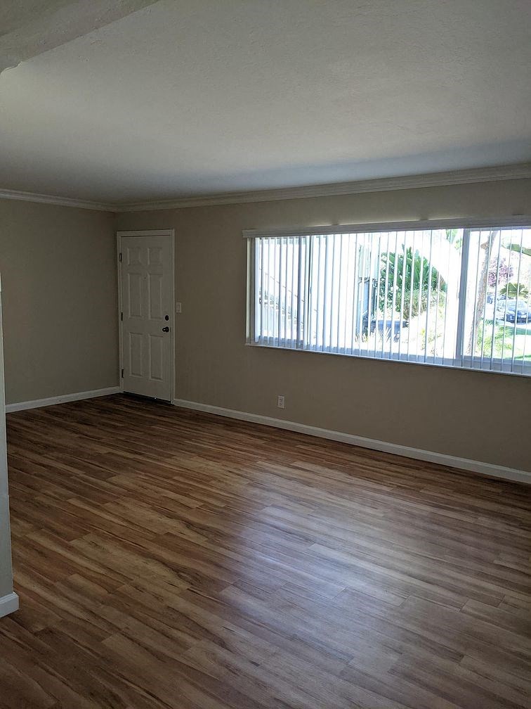 A room with wooden flooring and a window with blinds.