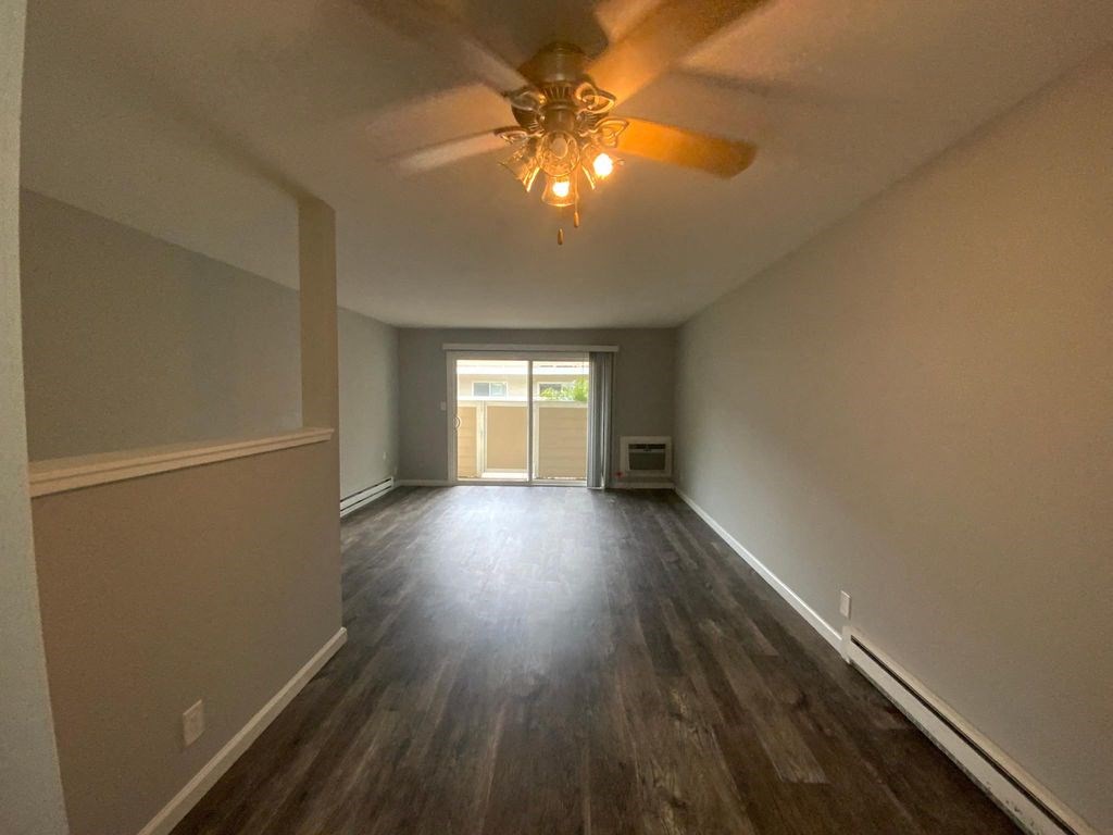 A room with a ceiling fan and wooden flooring.