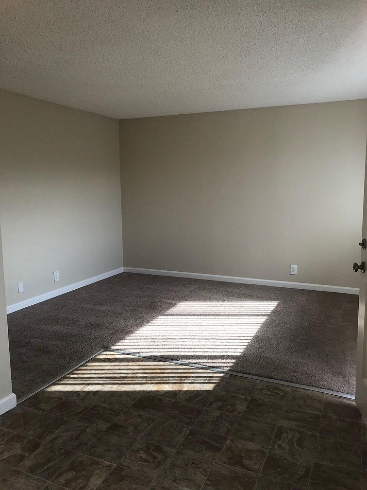 an empty living room with the sun shining through the window