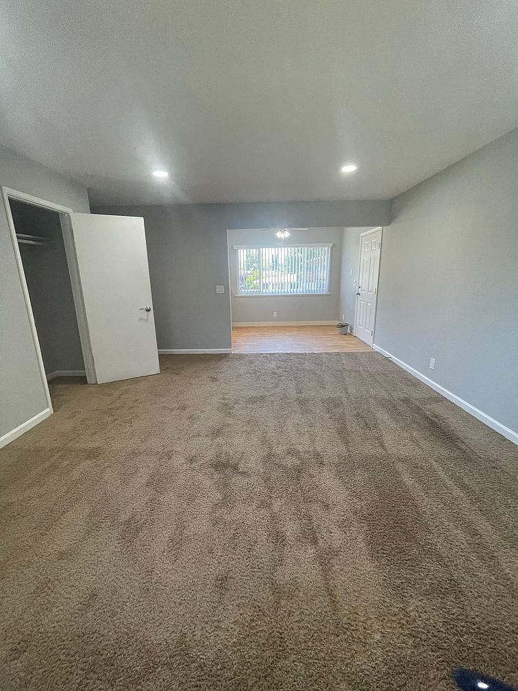 an empty living room with a carpeted floor and a window