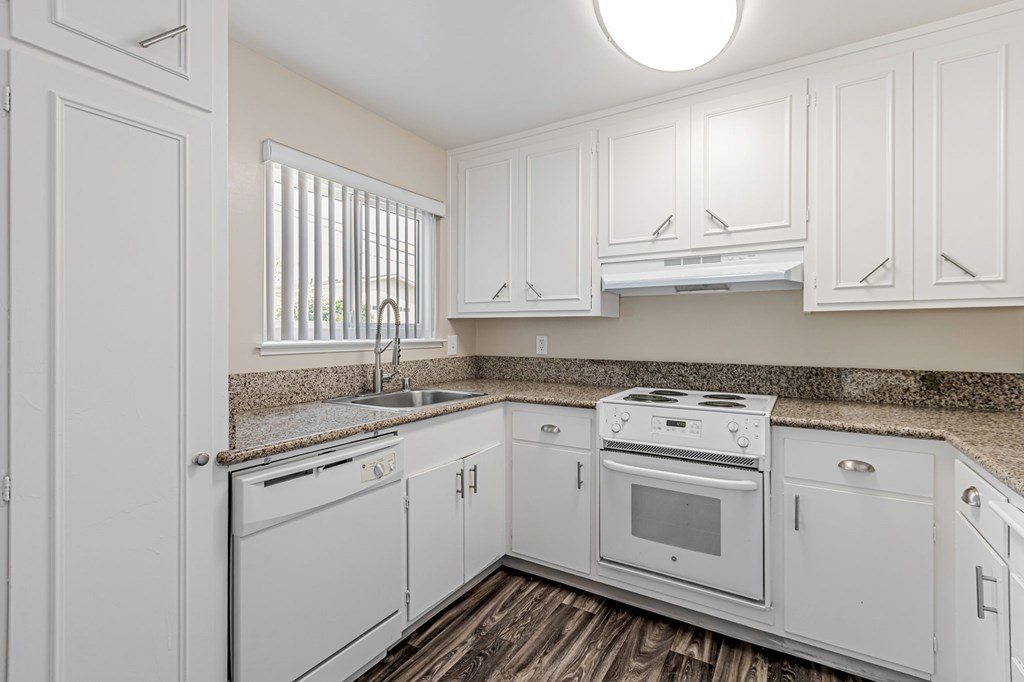 A white kitchen with a sink, stove, and oven.