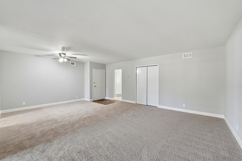 A spacious room with a ceiling fan and carpeted floor.
