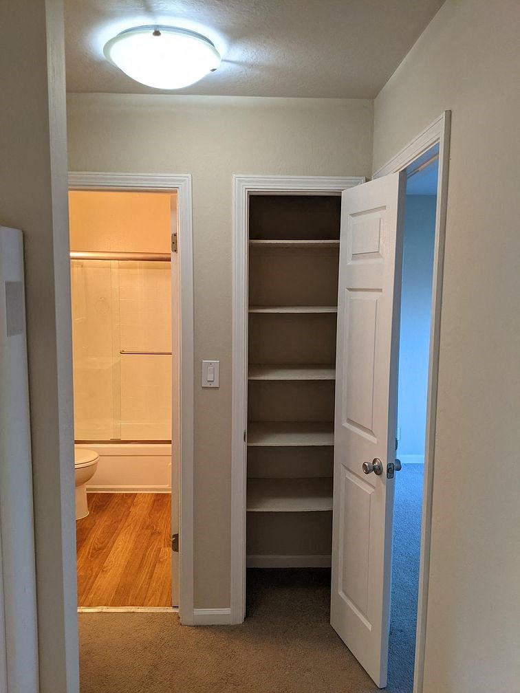 A white door is open to a room with a toilet and shelves.