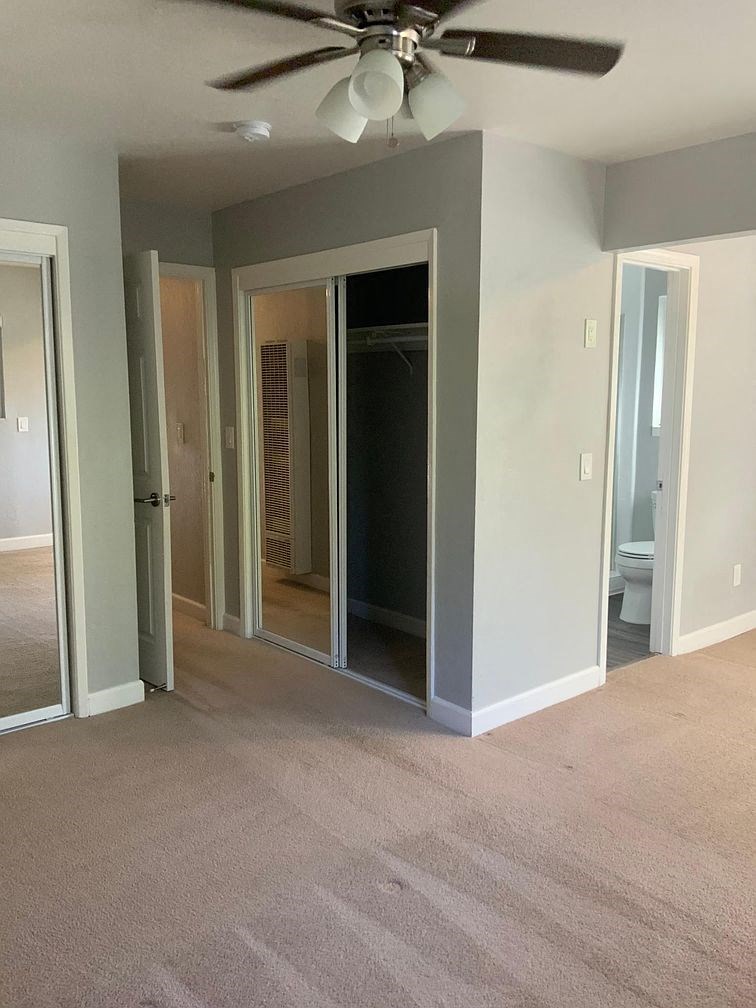 A room with a ceiling fan and a carpeted floor.