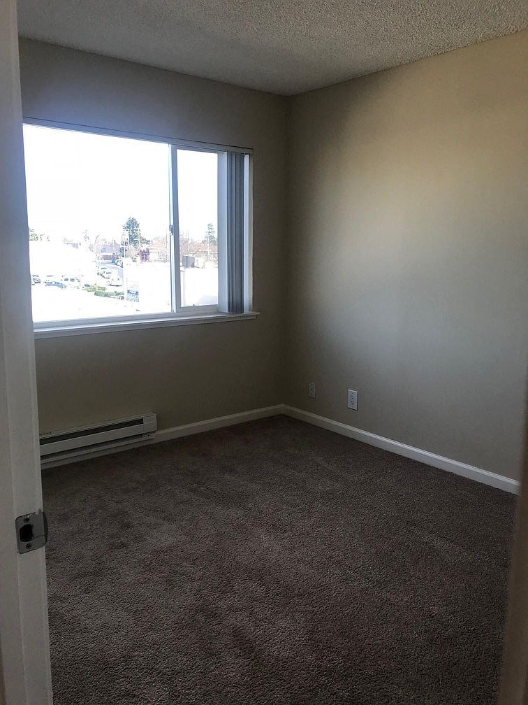 an empty room with a large window and carpet