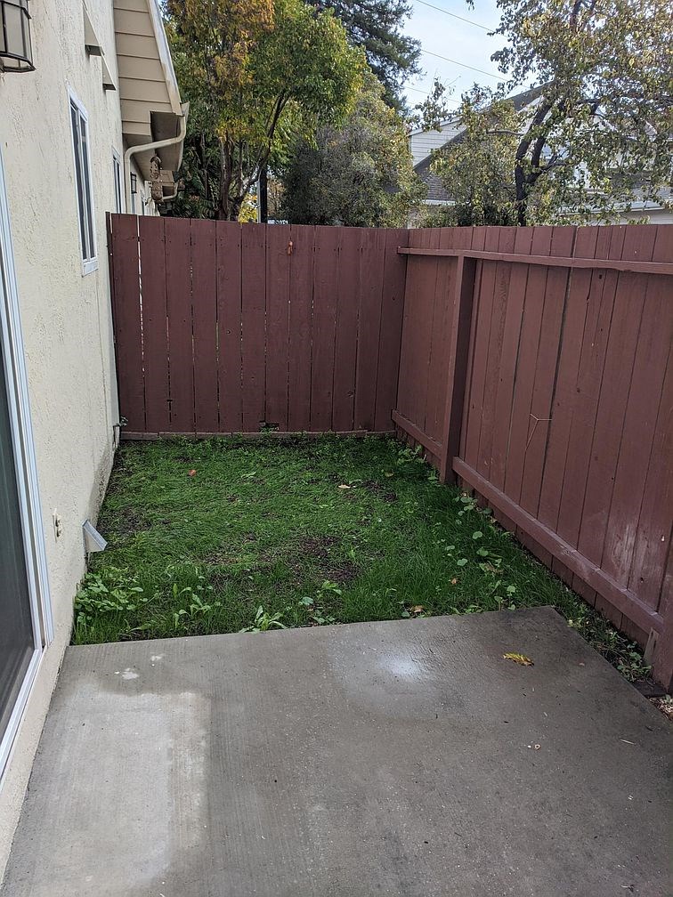 a backyard with a sidewalk and a fence