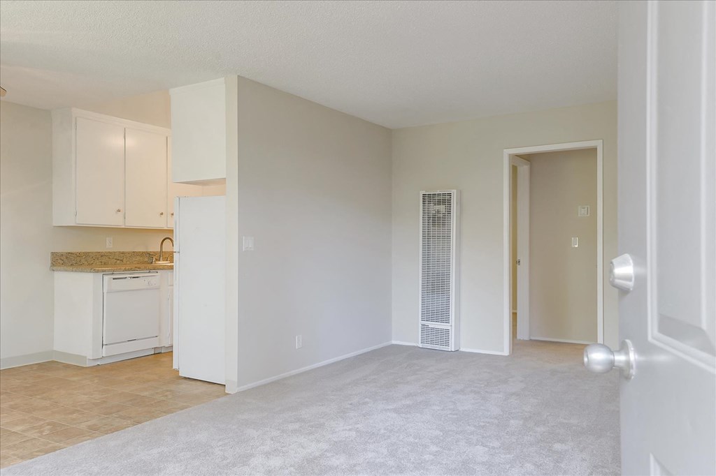 an empty living room and kitchen with an open door