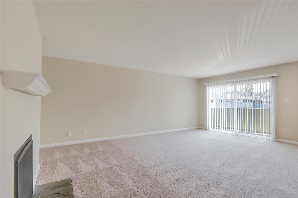 an empty living room with a sliding glass door to a balcony