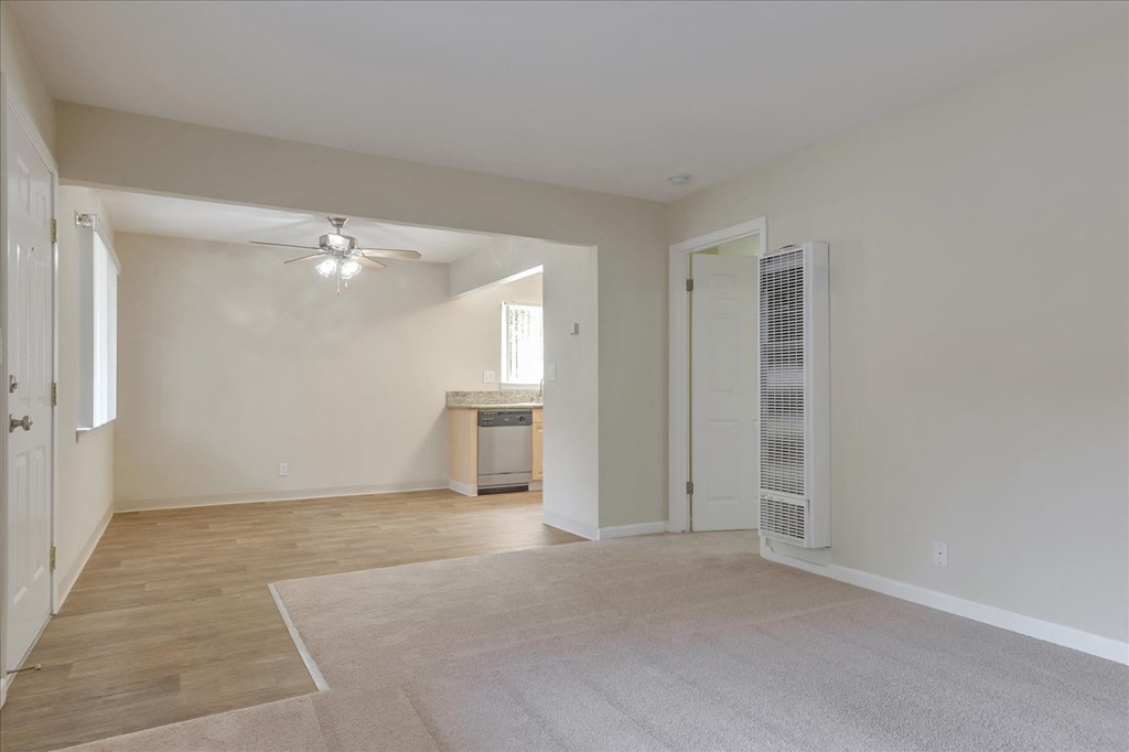an empty living room with a ceiling fan and a door to a bathroom