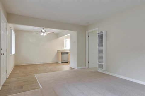 an empty living room with a ceiling fan and a door to a bathroom