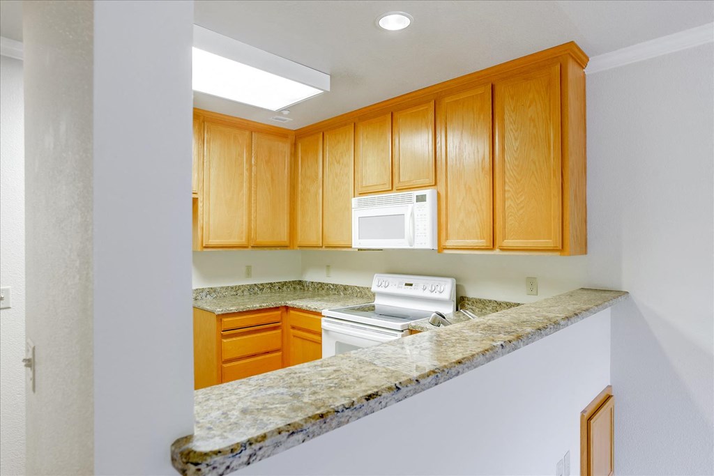 A kitchen with wooden cabinets and a granite countertop.
