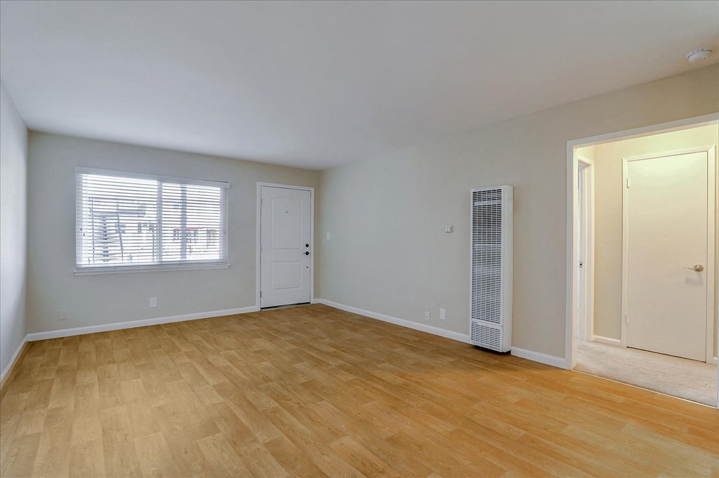 a living room with a hard wood floor and a door to a closet