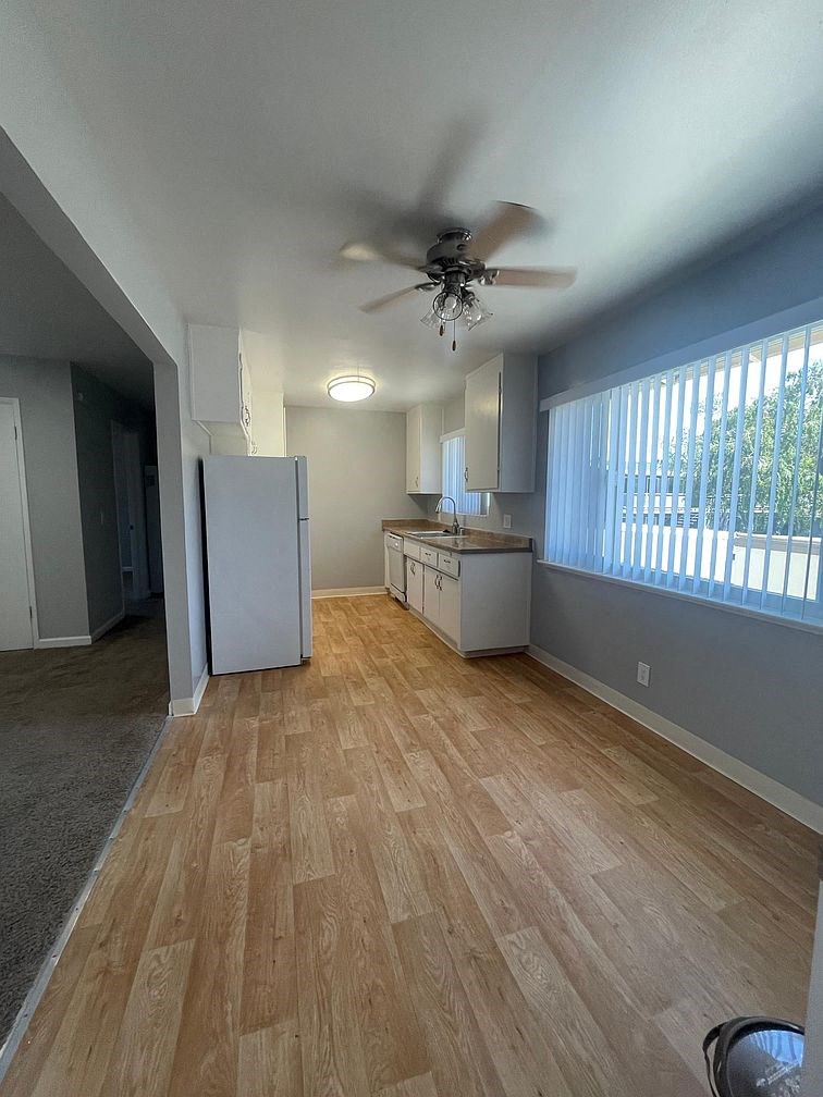 an empty living room and kitchen with a ceiling fan