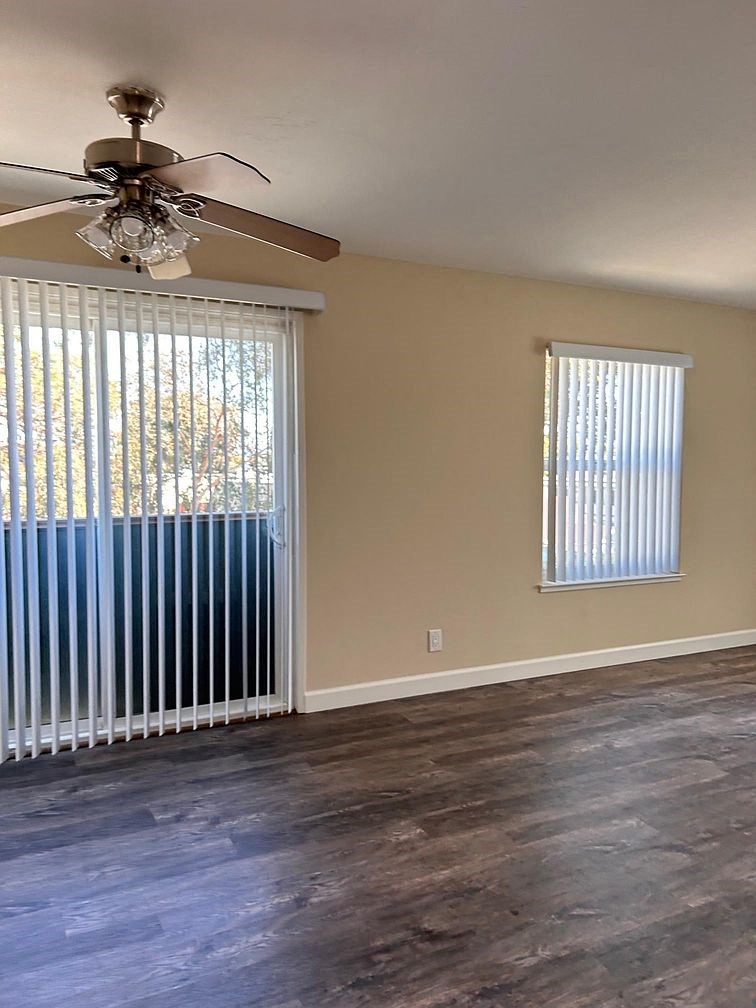 an empty living room with a ceiling fan and a window