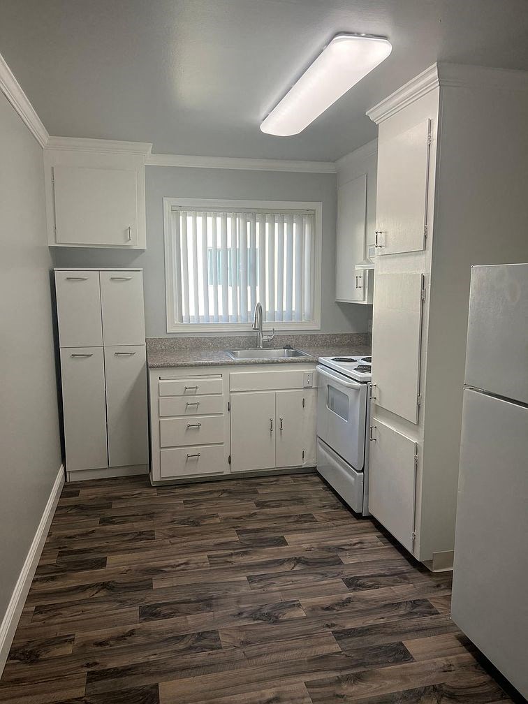 a kitchen with white appliances and a wood floor
