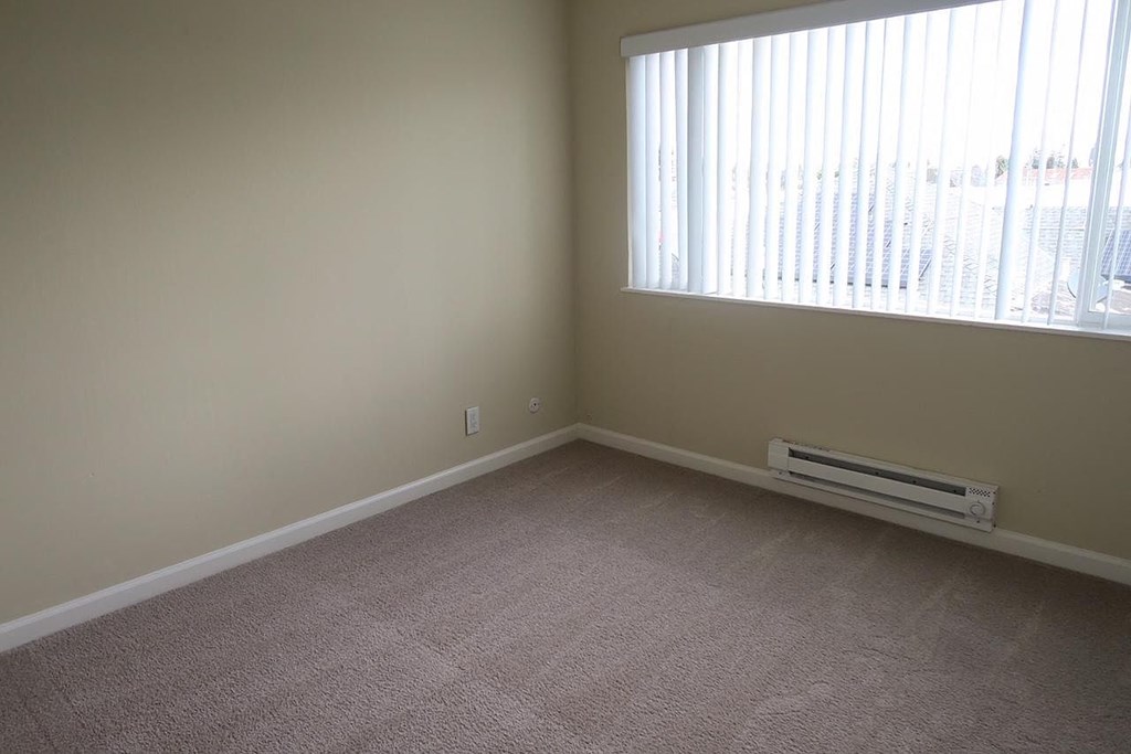 an empty living room with a large window and carpet