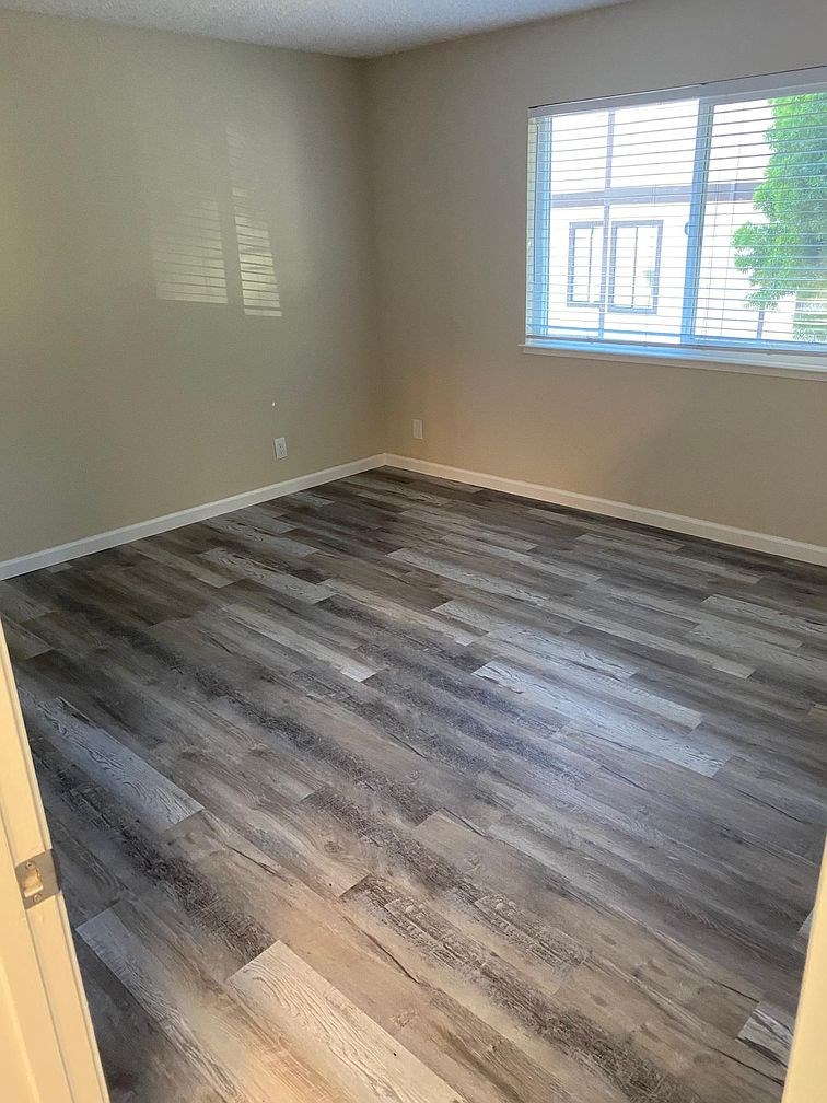 A room with a window and wooden flooring.