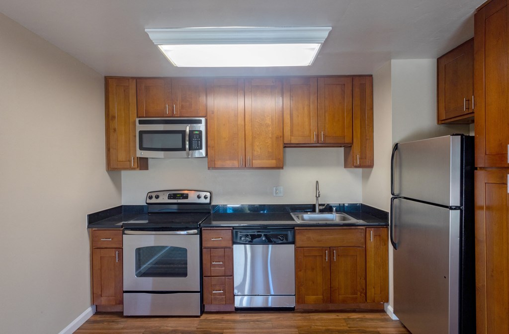 an empty kitchen with wooden cabinets and stainless steel appliances