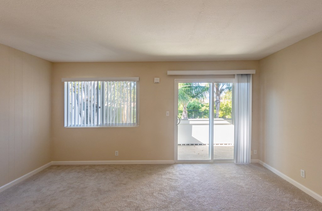 an empty living room with sliding glass doors to a patio