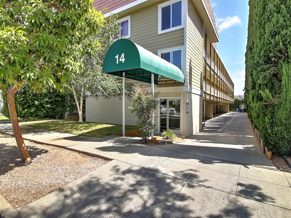 the front of a building with a green canopy and a sidewalk