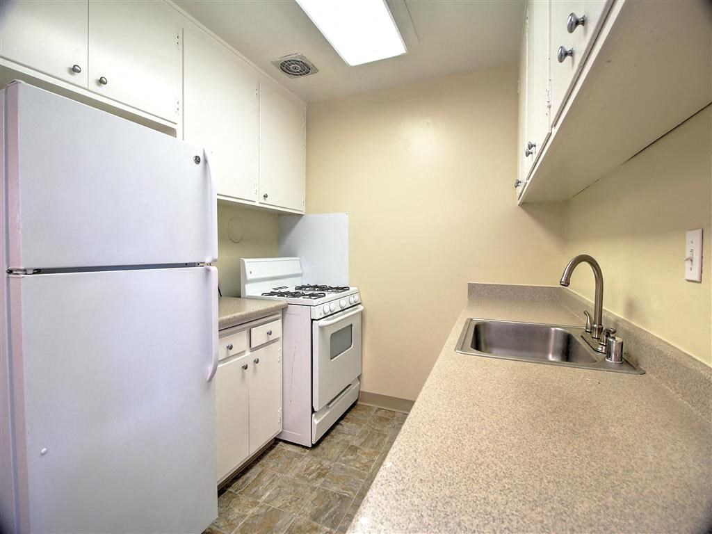 A kitchen with a white refrigerator, stove, and sink.