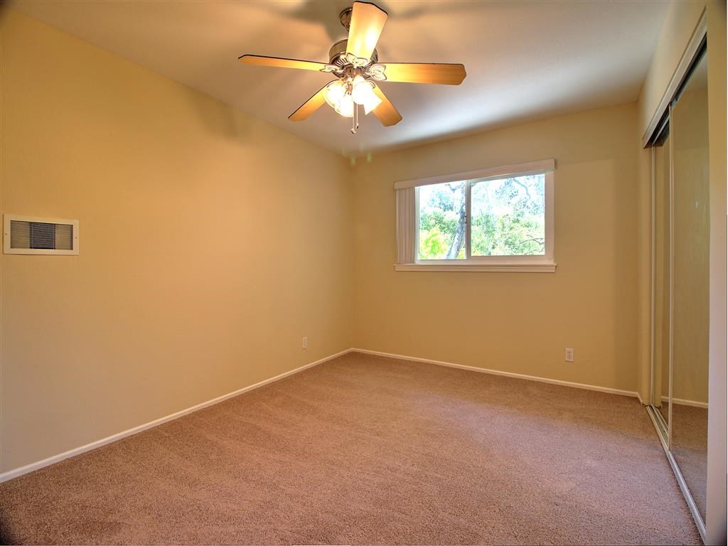 a empty room with a ceiling fan and a window