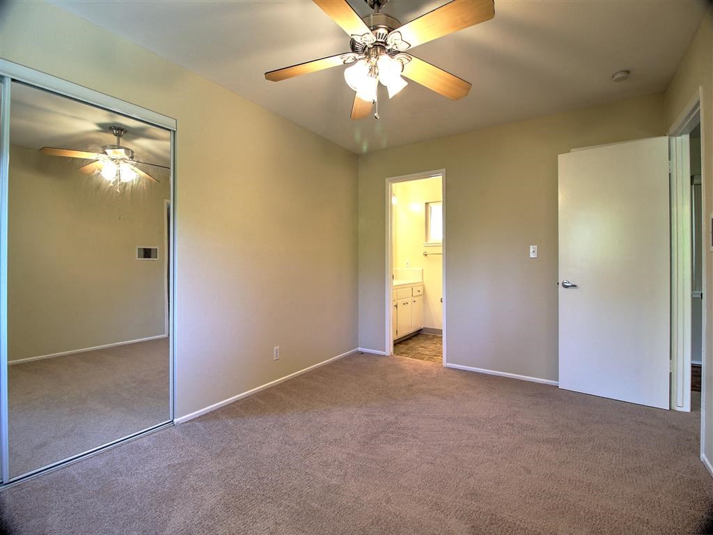 an empty living room with a ceiling fan and a mirror