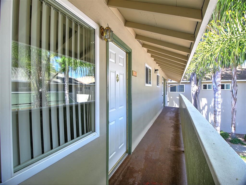 a long porch with a white door and a balcony