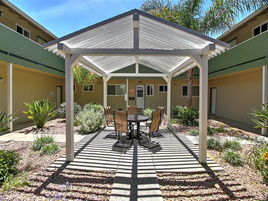 a patio with a table and chairs under a white pavilion