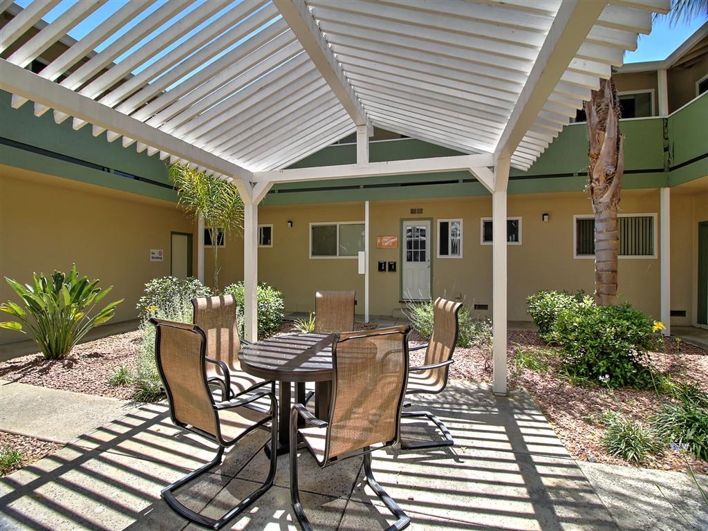 a patio with a table and chairs under a white roof