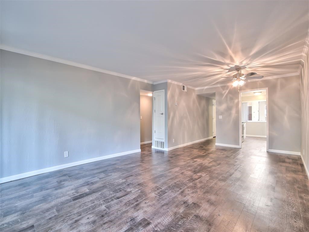 an empty living room with a ceiling fan